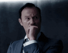 a man in a suit and tie is holding his hand to his chin