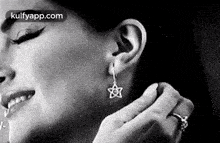 a woman is wearing earrings and a ring .