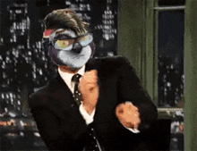 a man in a suit and tie with a mask on his face is dancing .