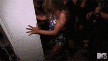 a woman in a blue dress is dancing in a room with a group of people .