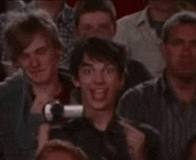 a group of people are sitting in a theatre watching a show and one of them is smiling