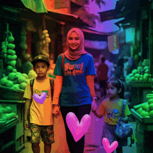 a woman wearing a blue shirt that says bumi walks down a street with two children