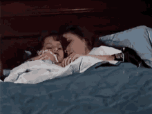 a woman and a child are laying in a bed together .