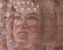 a woman wearing glasses has a lot of question marks around her head