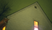 the roof of a house with a window lit up at night