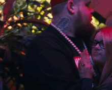 a man with a tattoo on his neck is holding a woman