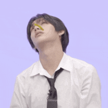a young man in a white shirt and tie is eating a candy .