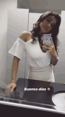 a woman taking a selfie in front of a mirror with the words buenos dias on the bottom