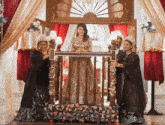 a woman in a gold dress is standing on a balcony surrounded by women in black dresses