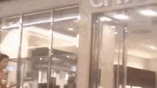 a man is standing in front of a store with a glass door .