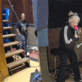 a woman singing into a pink microphone with a man standing behind her