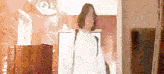 a woman in a white sweater is walking through a hallway .