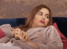 a woman in a robe is laying on a couch and making a face