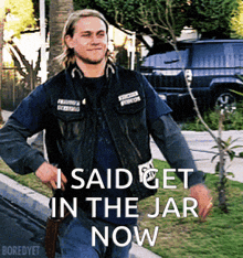 a man walking down the street with the words " i said get in the jar now " below him