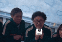a group of people are sitting in a room and one of them is holding a picture of a man in glasses .