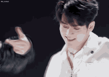 a man in a white jacket is smiling and pointing