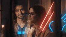a man and a woman are standing next to each other under a neon sign .
