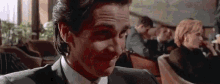 a man in a suit and tie is making a funny face in a crowded room .