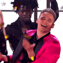 a man in a pink suit is laughing and clapping his hands