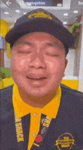a man wearing a black hat and a yellow shirt with the shawarma shack written on it