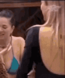 a woman in a blue bikini top is standing next to another woman