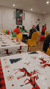 a group of people sitting at tables with a sign that says merry christmas on it