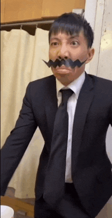 a man in a suit and tie is making a funny face with a fake mustache .