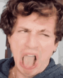 a man with curly hair is sticking his tongue out and making a funny face .