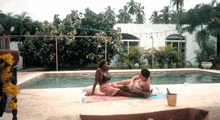 a man and woman are laying on a blanket by a pool