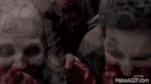 a group of zombies are standing next to each other with blood on their faces .