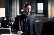 a man in a suit and tie stands in front of a mirror