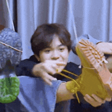 a man is holding a pair of boots in his hands and making a funny face .