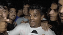 a group of people are standing around a man in a white shirt .