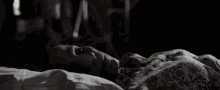 a woman is laying on a bed with her mouth open in a dark room .