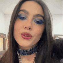 a close up of a woman 's face with blue eyeshadow and a choker