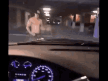 a man without a shirt is walking in a parking garage .