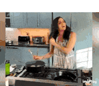 a woman is cooking in a kitchen and singing into a pan .
