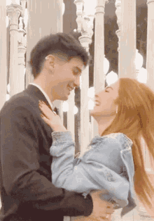 a man in a suit holds a woman in a denim jacket in his arms