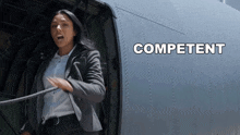 a woman in a suit is pulling a rope in front of an airplane with competent written on the side