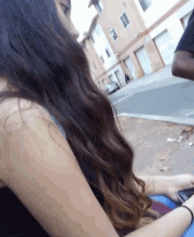 a woman with long brown hair is sitting on the sidewalk