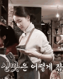 a woman wearing an apron and a turtleneck is looking at her phone