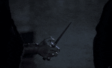 a person is holding a glass in their hand in a dark room