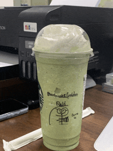 a green starbucks frappuccino with whipped cream and a drawing of an owl on it