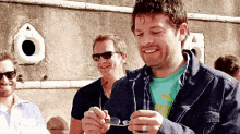 a man wearing sunglasses is smiling while holding a pair of glasses in his hand .