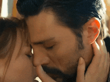 a man and woman are kissing and the woman is touching his face