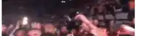 a blurry picture of a crowd of people standing in a dark room .