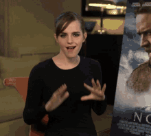 a woman stands in front of a poster for the movie now
