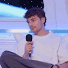 a man is sitting down holding a microphone .