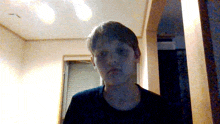 a boy in a black shirt is standing in a dark room