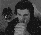 a man wearing headphones is smoking a cigarette in front of a microphone in the rain .
